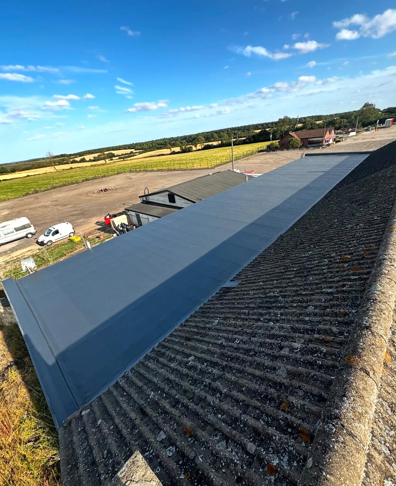 Long commercial flat roof kept clean and maintained alongside an older sheet roof